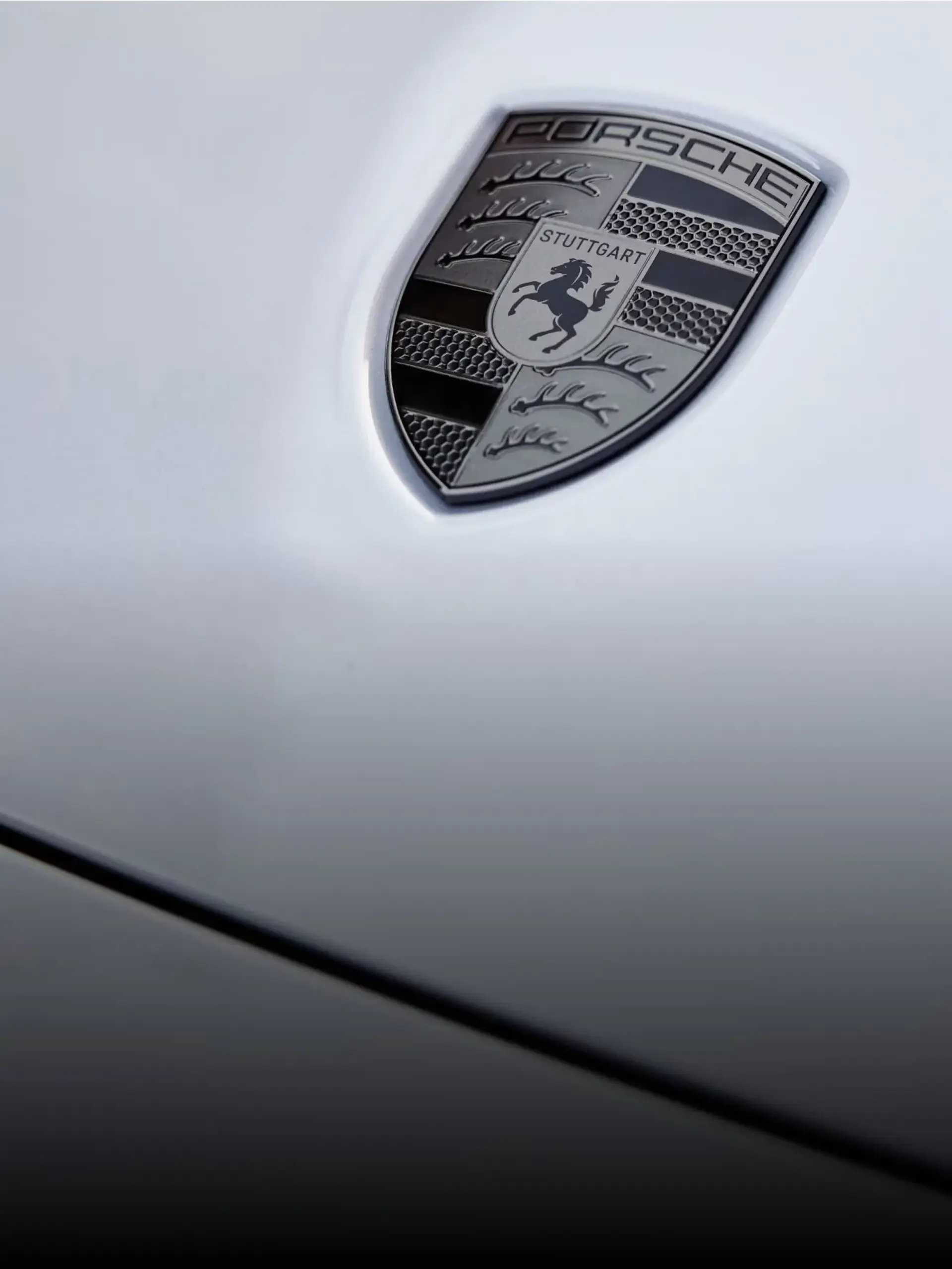 Nærbillede af et Porsche-logo på motorhjelmen af en bil.