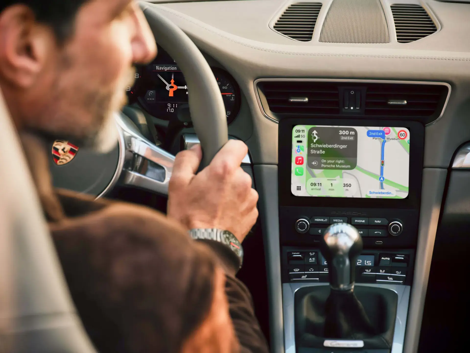 En person kører en Porsche, hvor bilens midterdisplay viser et navigationskort.