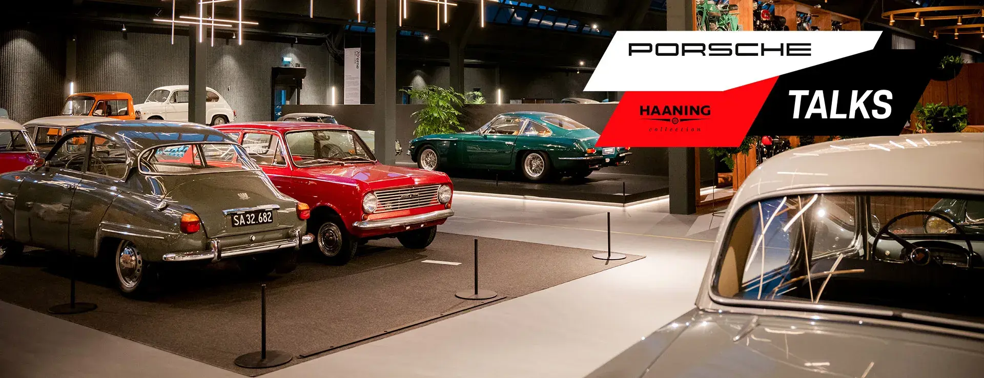 Udstillingshal med klassiske biler fra Haanning Collection og grafisk logo for “Porsche Talks” i højre side.