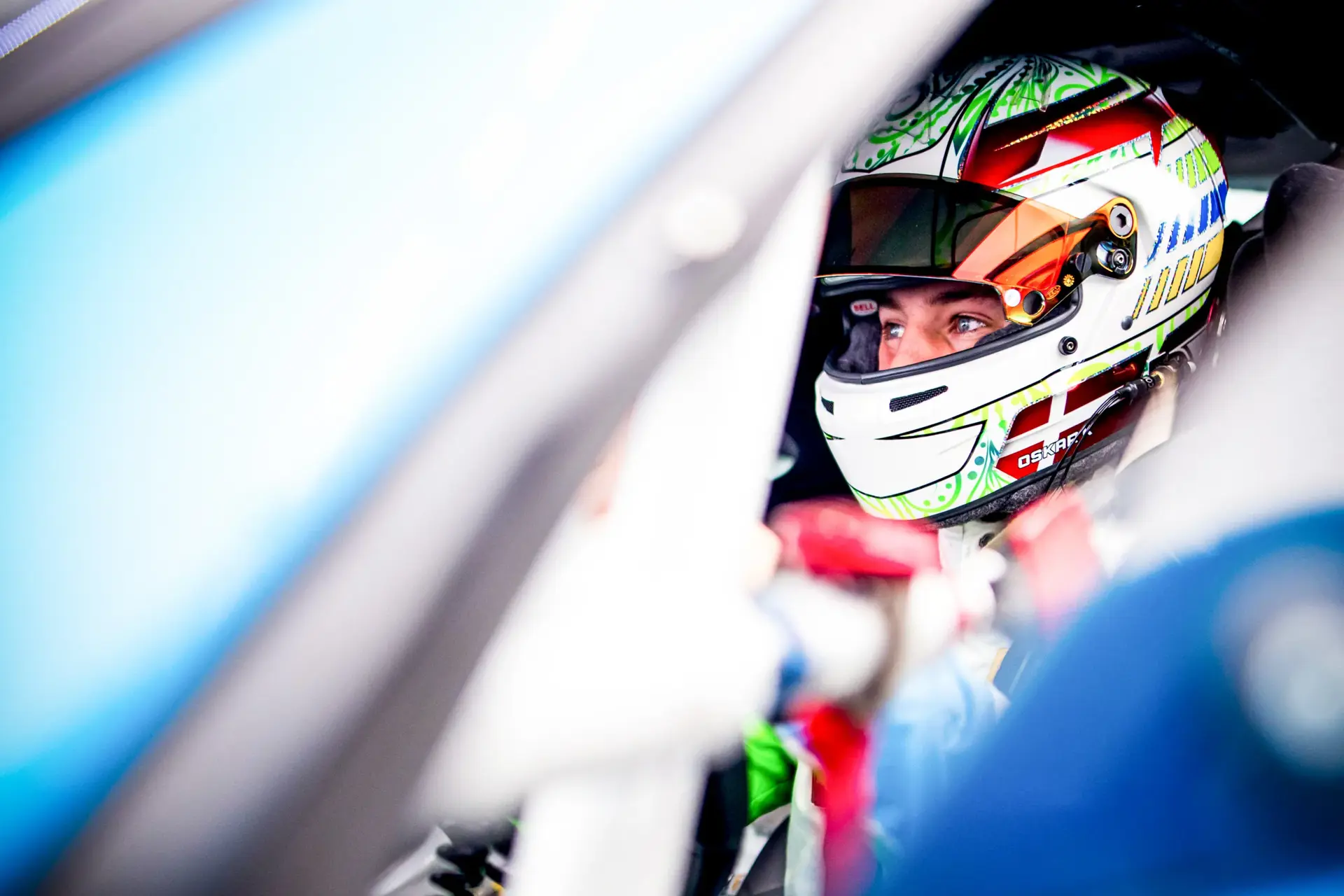 Racerkører med farverig hjelm ses inde i en GT4-racerbil på Hockenheim.