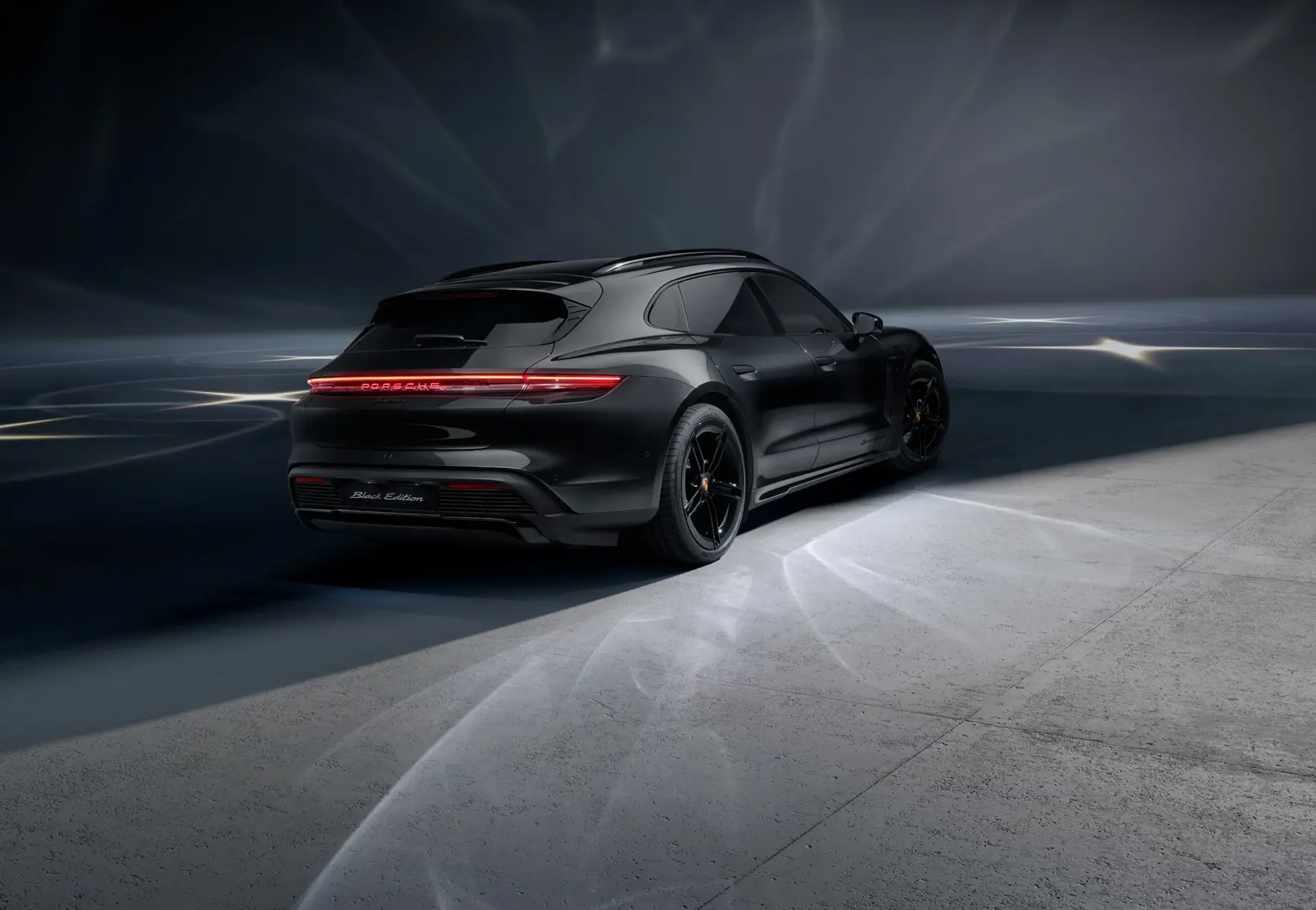 Sort Porsche Taycan Black Edition set skråt bagfra i et mørkt, stemningsfuldt studie.