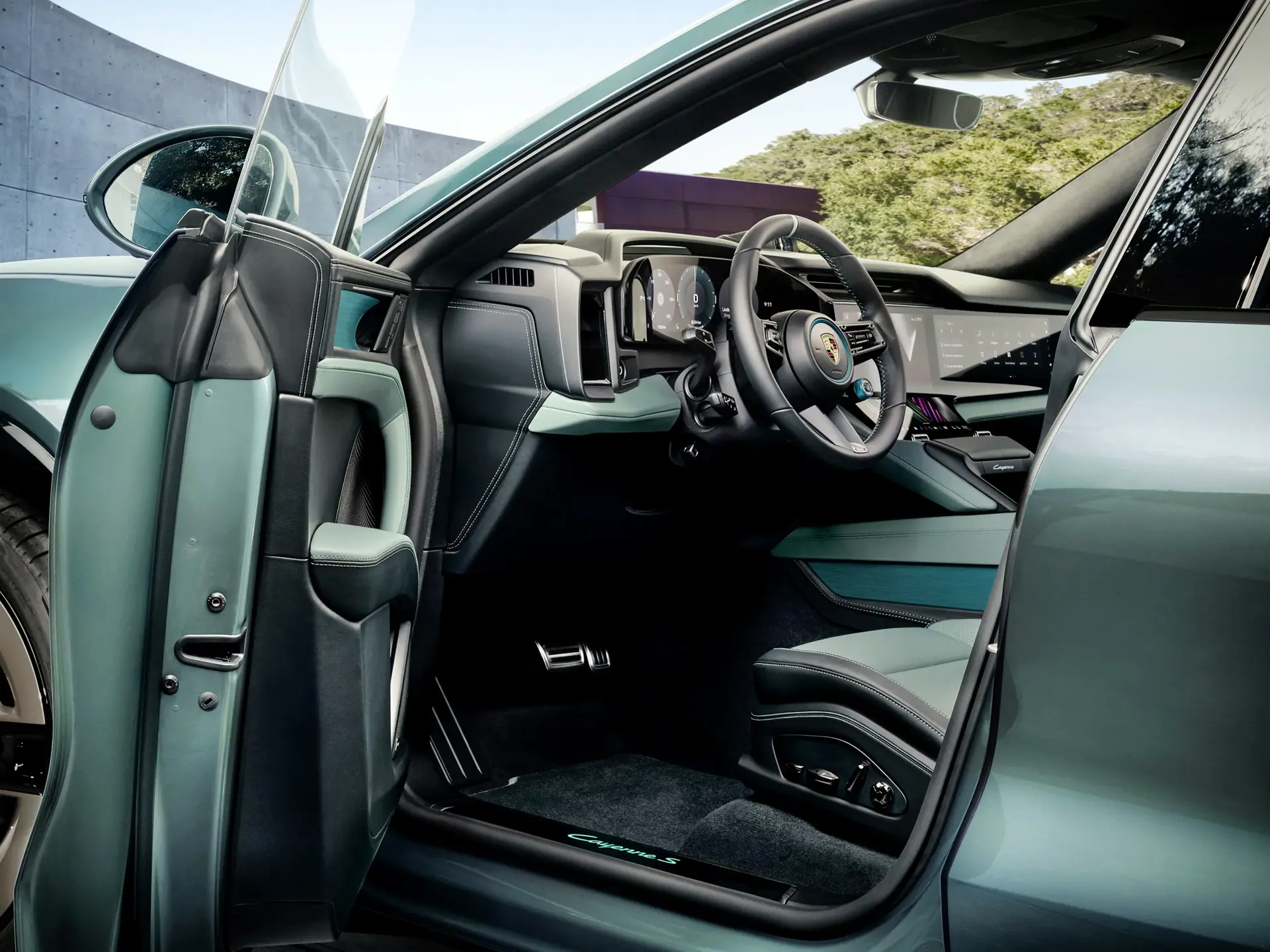 Åben førerdør til en turkis Porsche Cayenne, der viser et moderne førerhus med lædersæder og digitale instrumenter.
