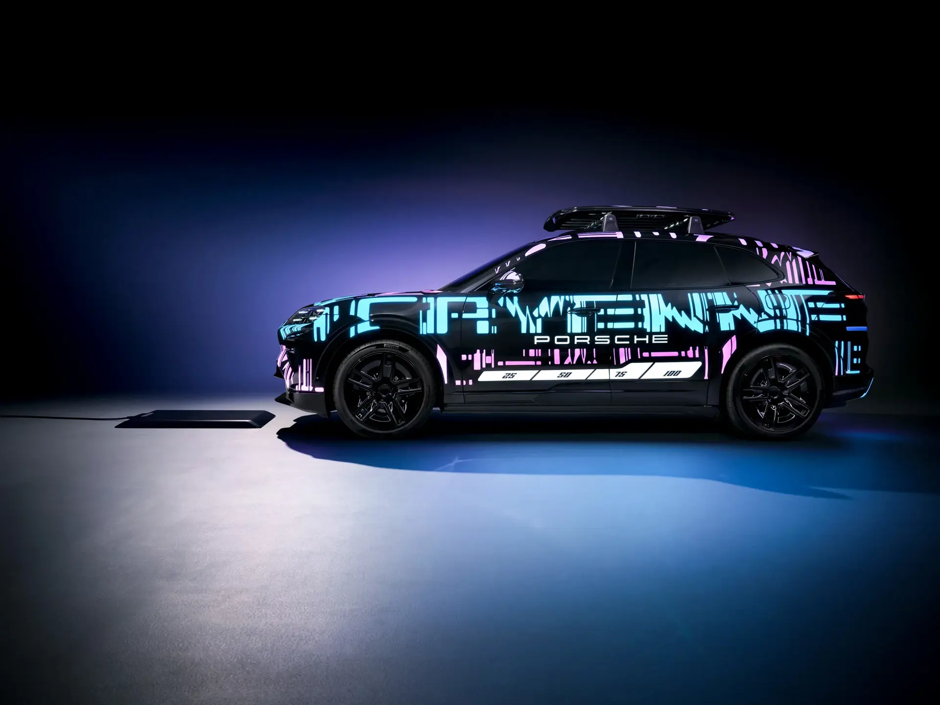 En Porsche Cayenne E-Hybrid SUV med neonfarvet, futuristisk folie står i profil på en mørk, oplyst scene.