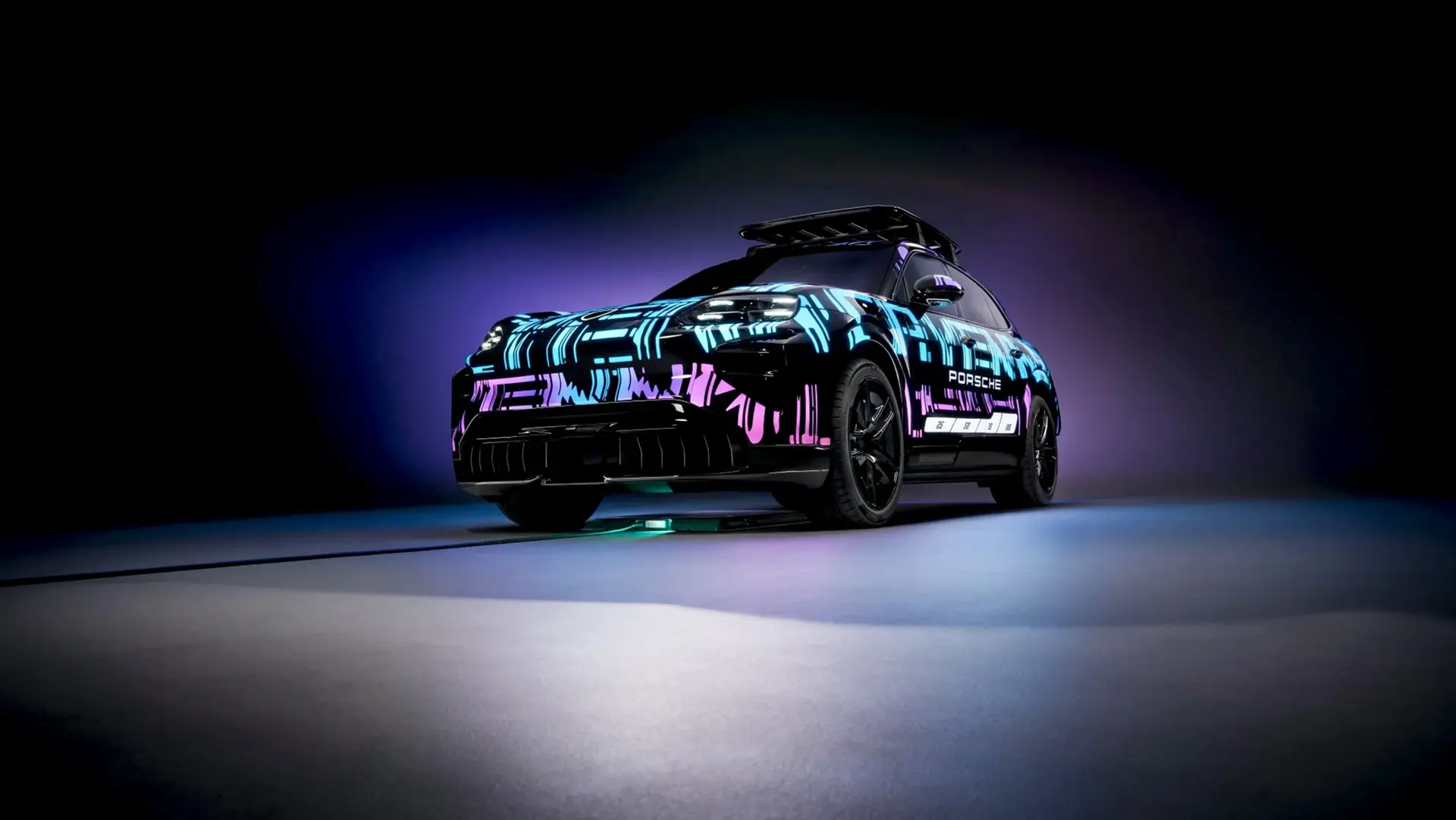 En futuristisk Porsche SUV med farverigt neon-camouflage står oplyst i et mørkt studie.