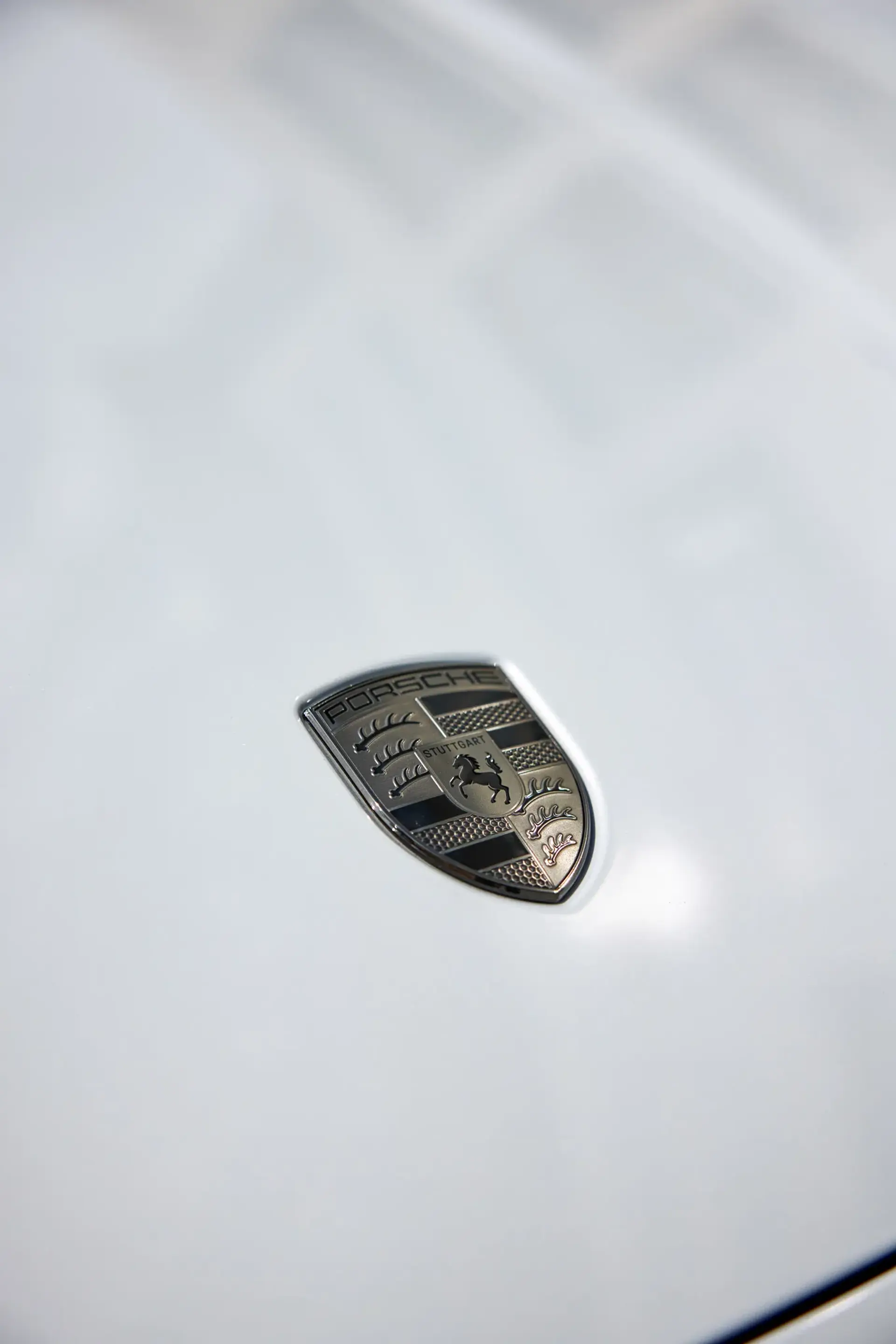 Porsche-logoet ses tæt på på den hvide motorhjelm på en Taycan.