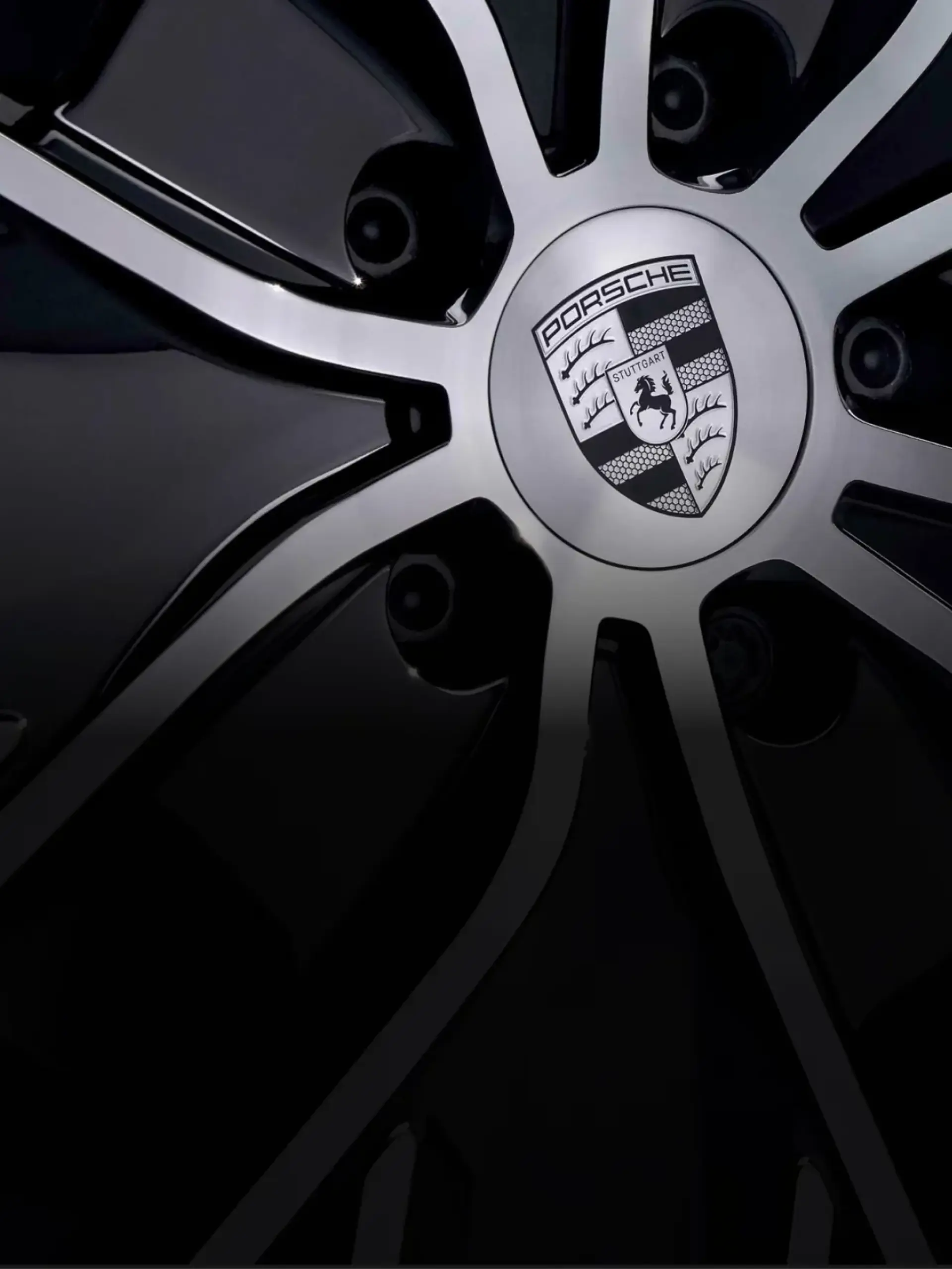 Nærbillede af en skinnende sort alufælg med Porsche-logo i centrum.