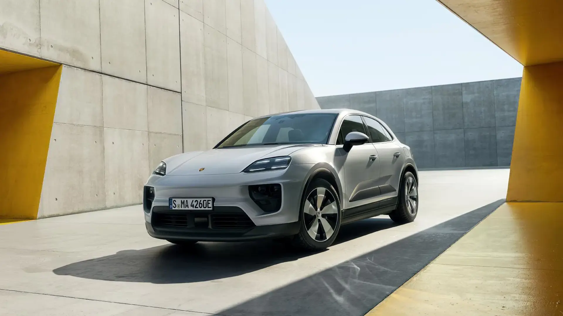 Sølvfarvet Porsche Macan med Advanced-pakke holder parkeret i et moderne, betonomgivet byrum.