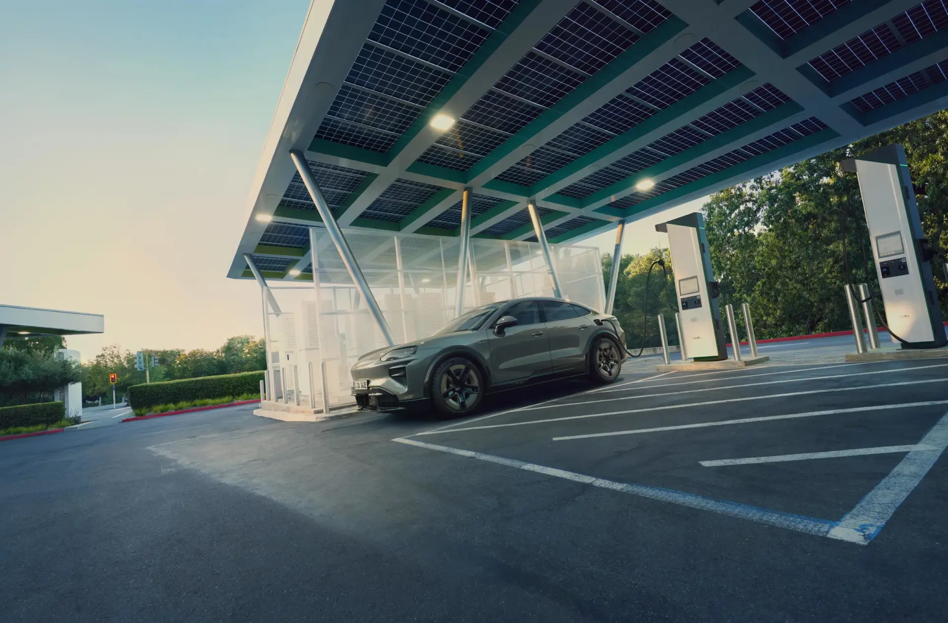 En grå elektrisk SUV holder parkeret ved en moderne lynladestation med solcelleoverdækning.