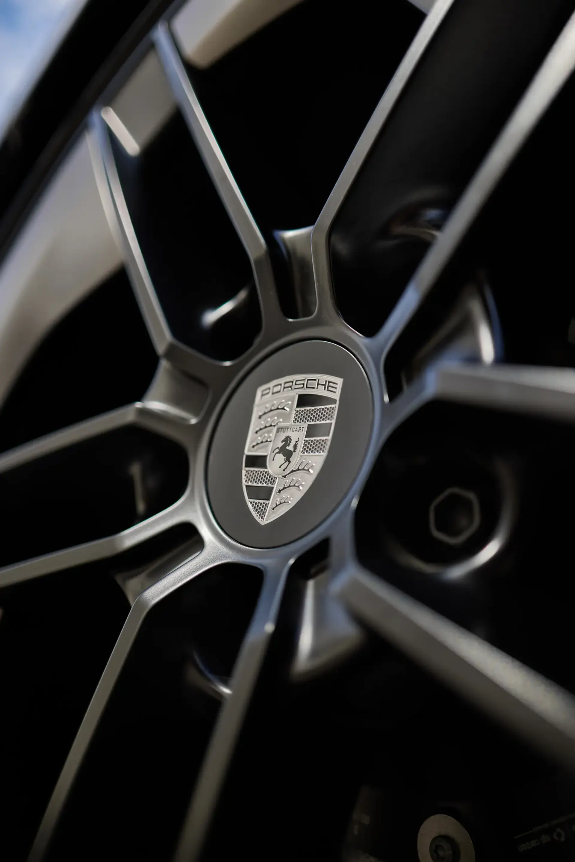 Nærbillede af en Porsche Taycan-fælg med tydeligt synligt Porsche-logo i midten.