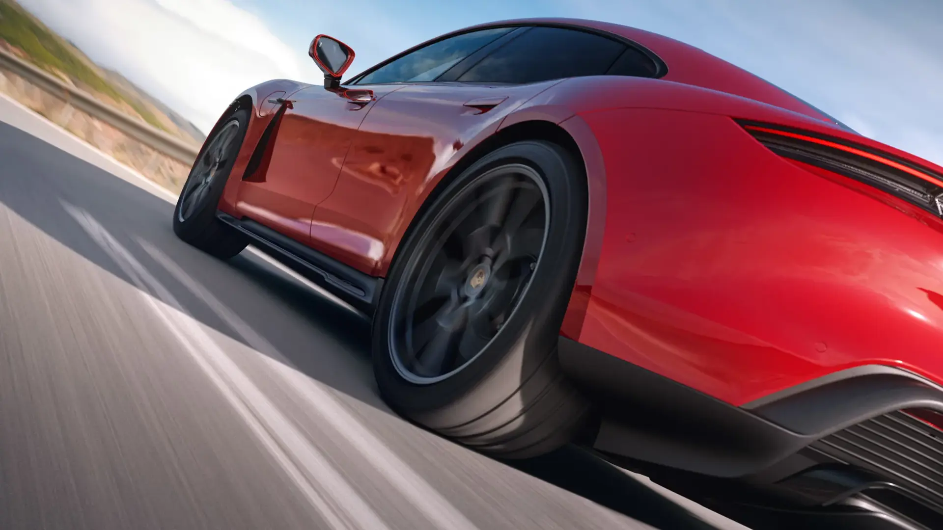 Rød Porsche Taycan GTS set tæt på bagfra i fart på en åben vej.