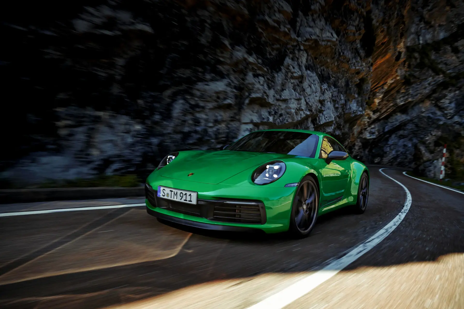 Grøn Porsche 911 Carrera T i fart på en snoet bjergvej.
