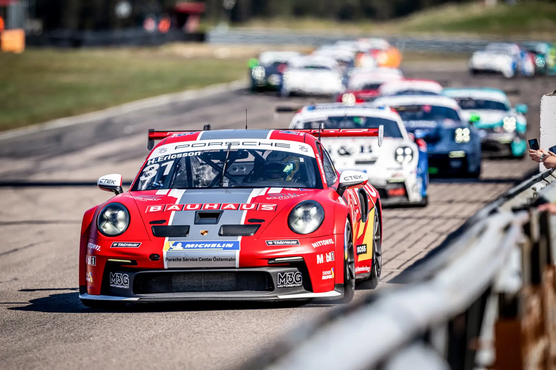 Rødt Porsche-løbsbil fører feltet under et Carrera Cup Scandinavia-løb på FDM Jyllandsringen i 2024.