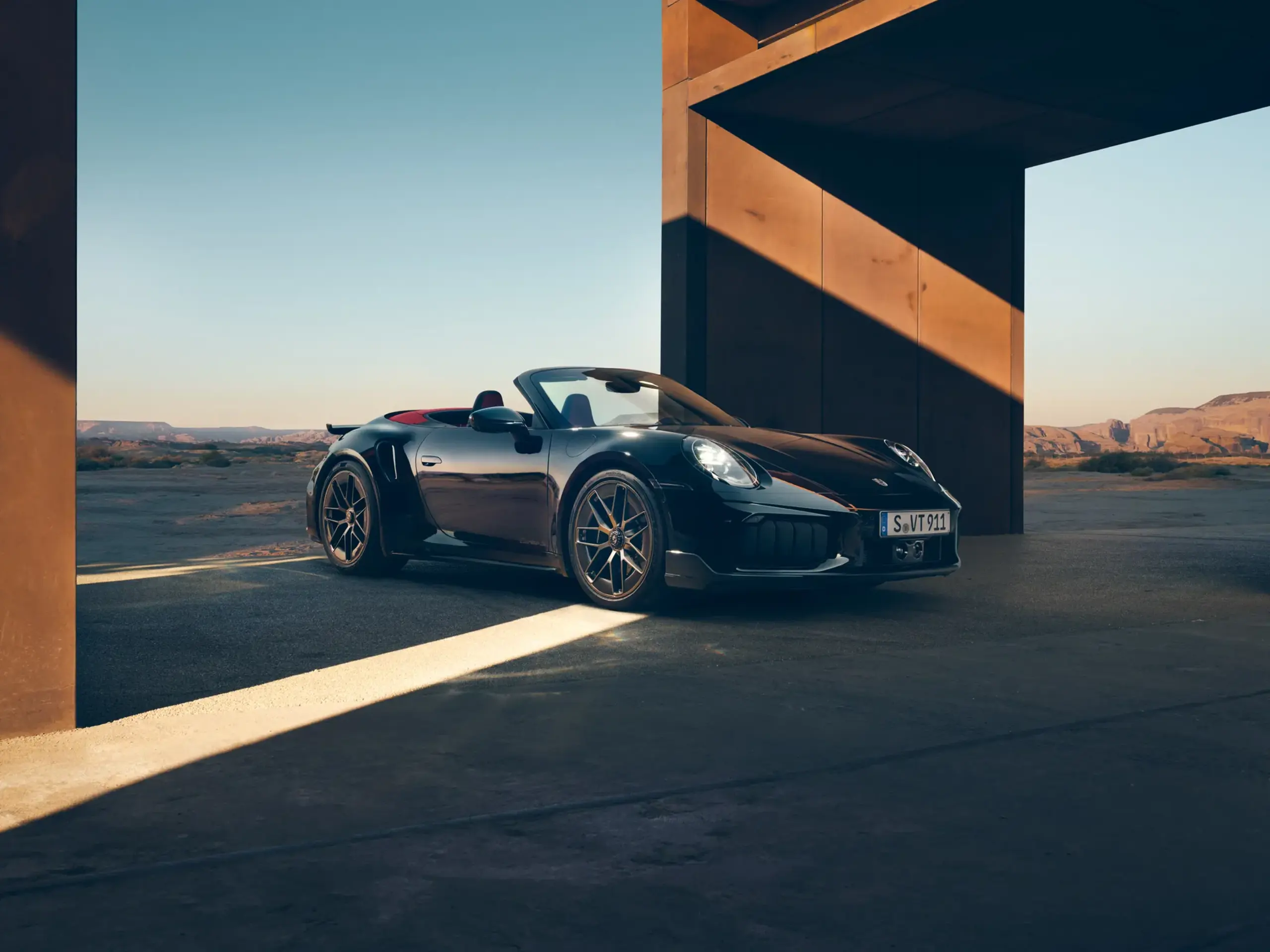 Luksuriøst interiør i en Porsche 911 Turbo S med rat, digital instrumentering og midterkonsol set fra førersædet.