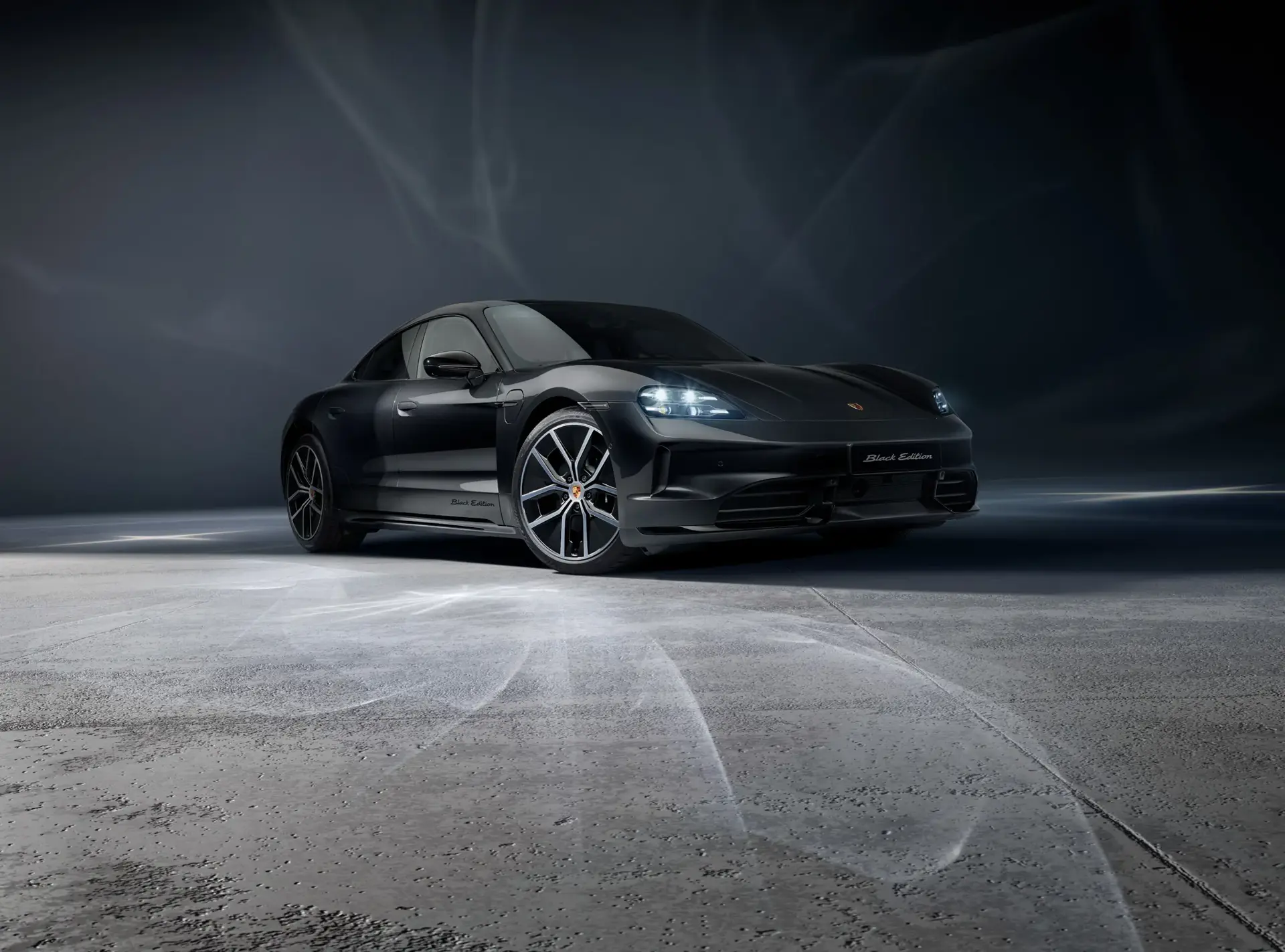 Sort Porsche Taycan Black Edition sportsvogn står oplyst i et mørkt, minimalistisk studie.