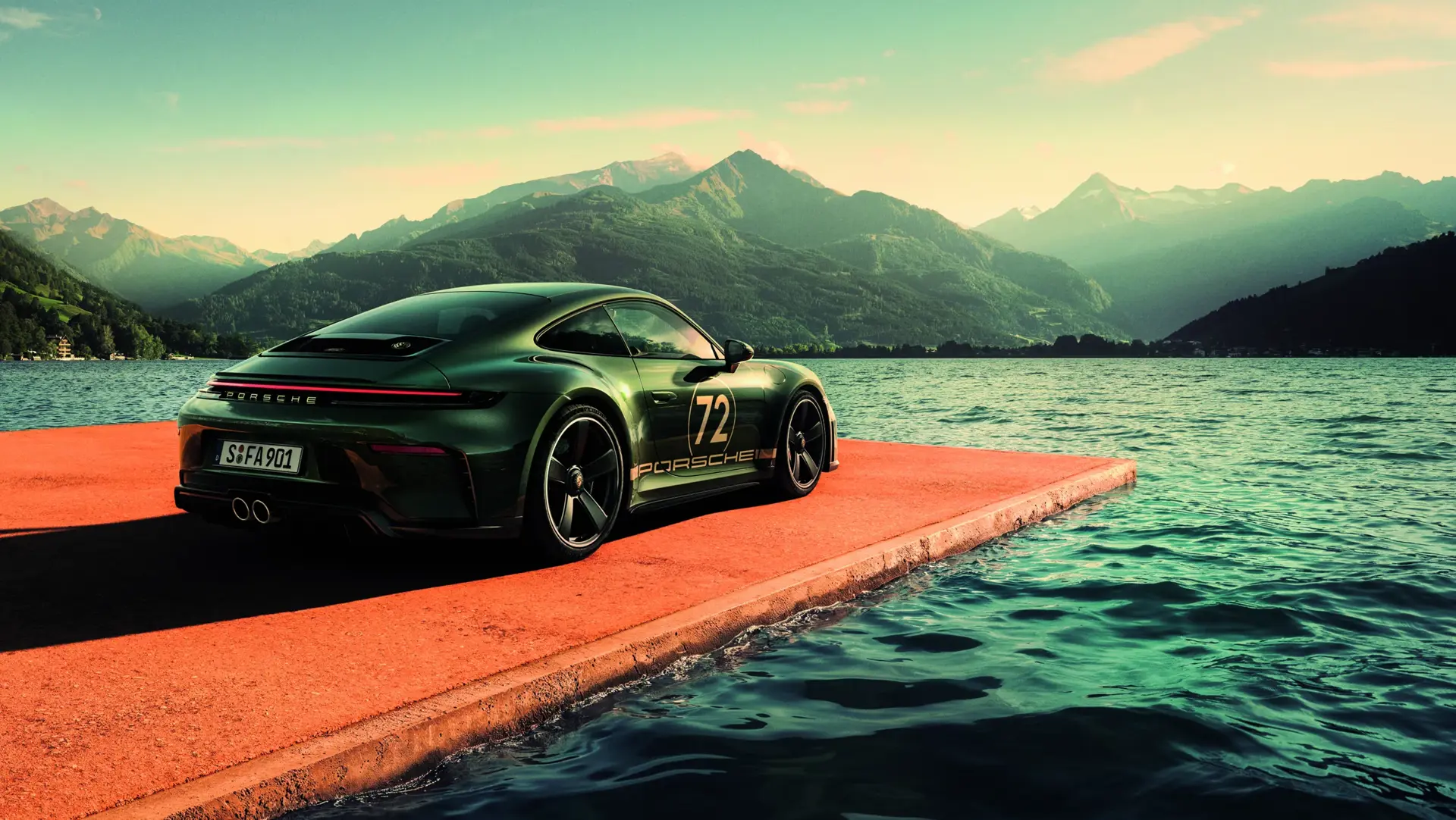 En mørkegrøn Porsche sportsvogn holder på en rød betonpier ved en sø omgivet af bjerge i solnedgang.