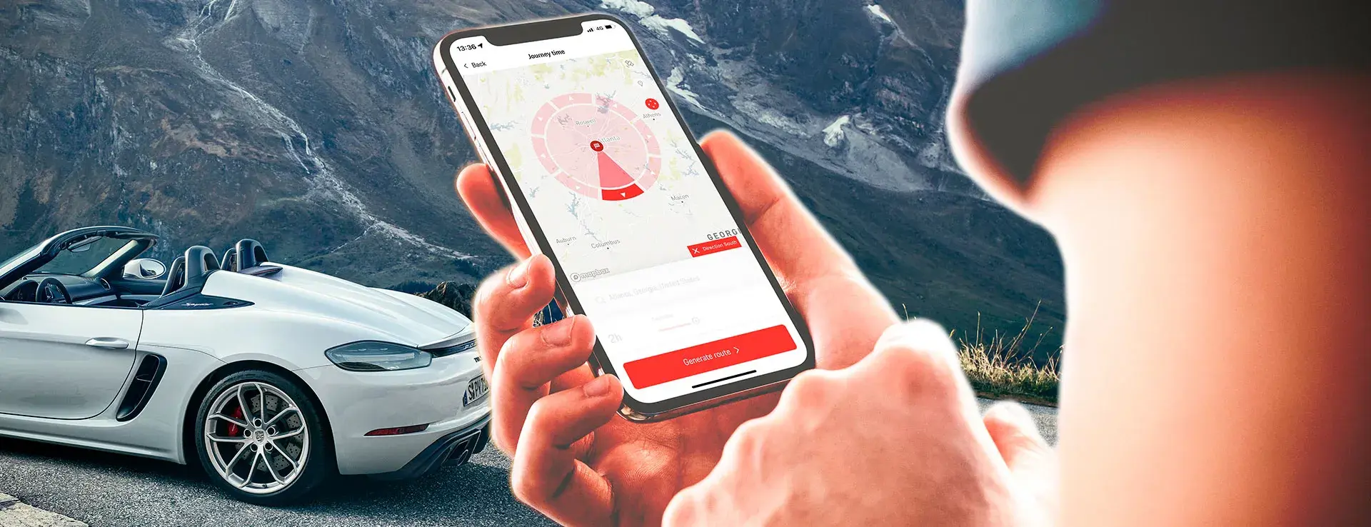 En person holder en smartphone med en ruteplanlægningsapp foran en hvid Porsche cabriolet parkeret i et bjerglandskab.