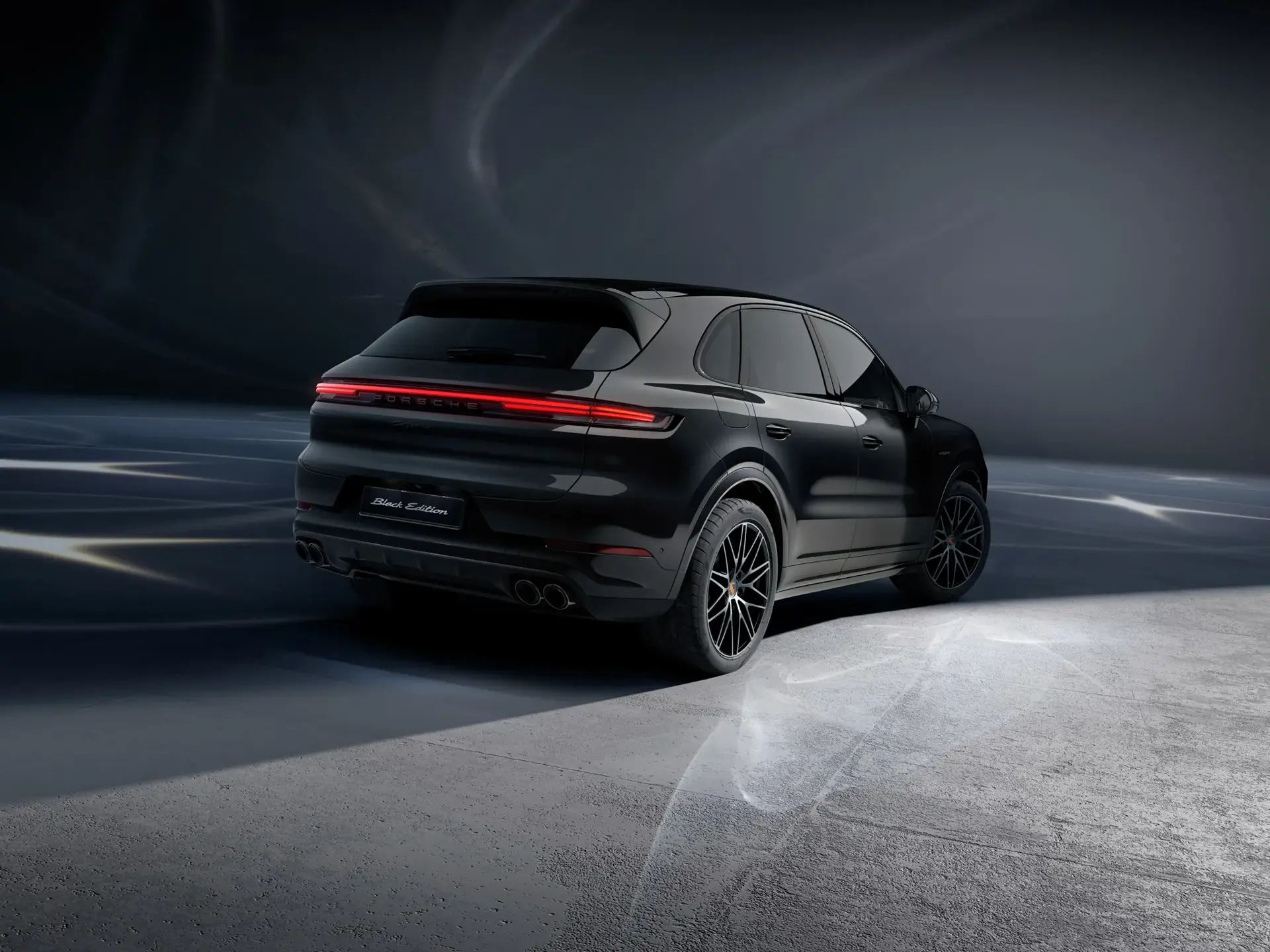 Sort Porsche Cayenne Black Edition SUV set bagfra i et mørkt, minimalistisk studie.