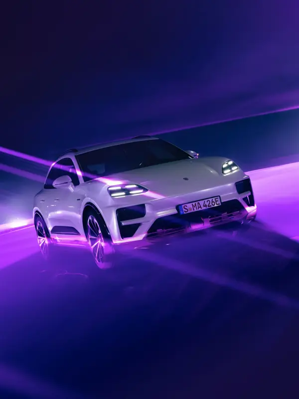 Hvid Porsche Macan Turbo fotograferet i fart i et futuristisk, lilla oplyst miljø.