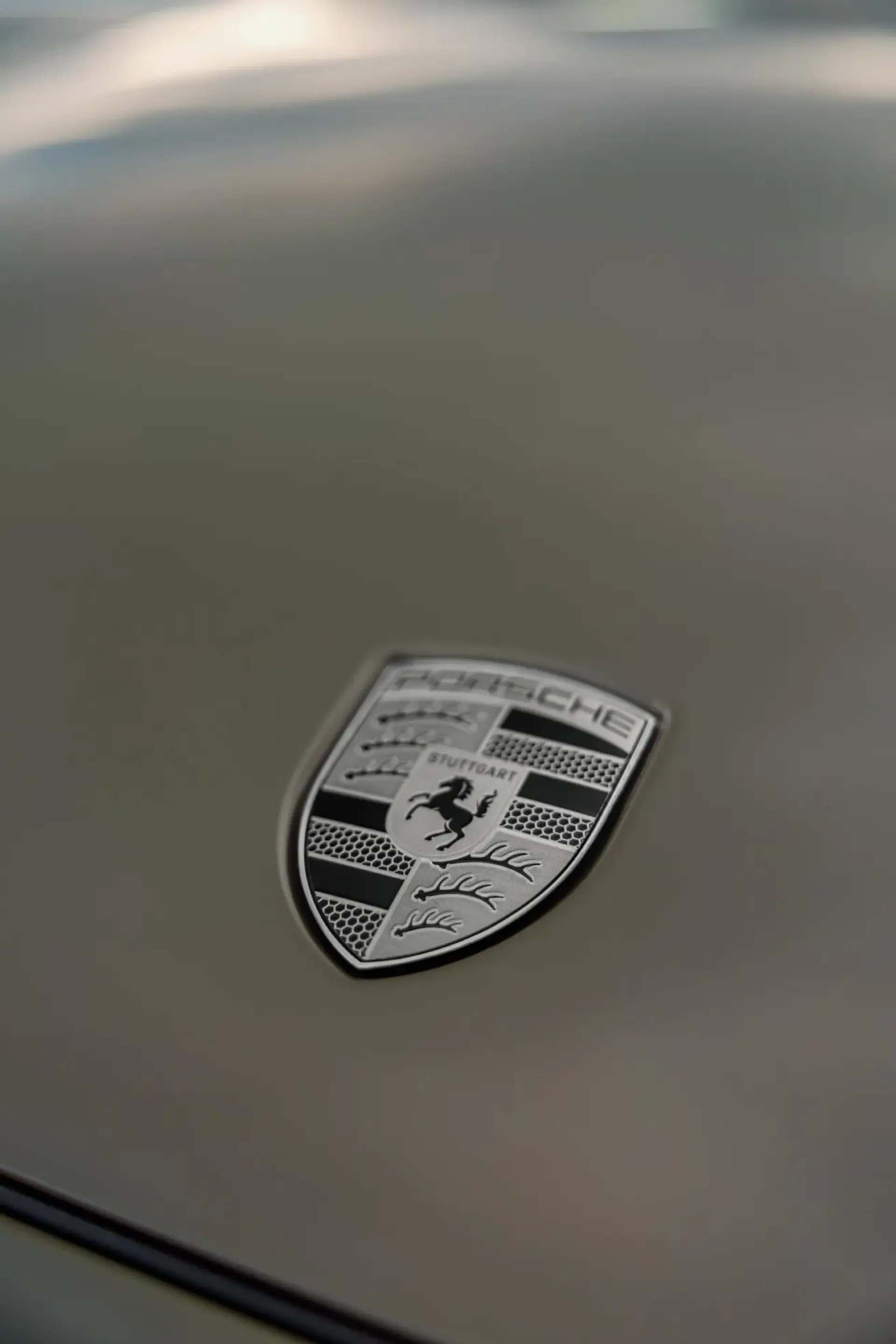 Nærbillede af et Porsche-logo på motorhjelmen af en bil.