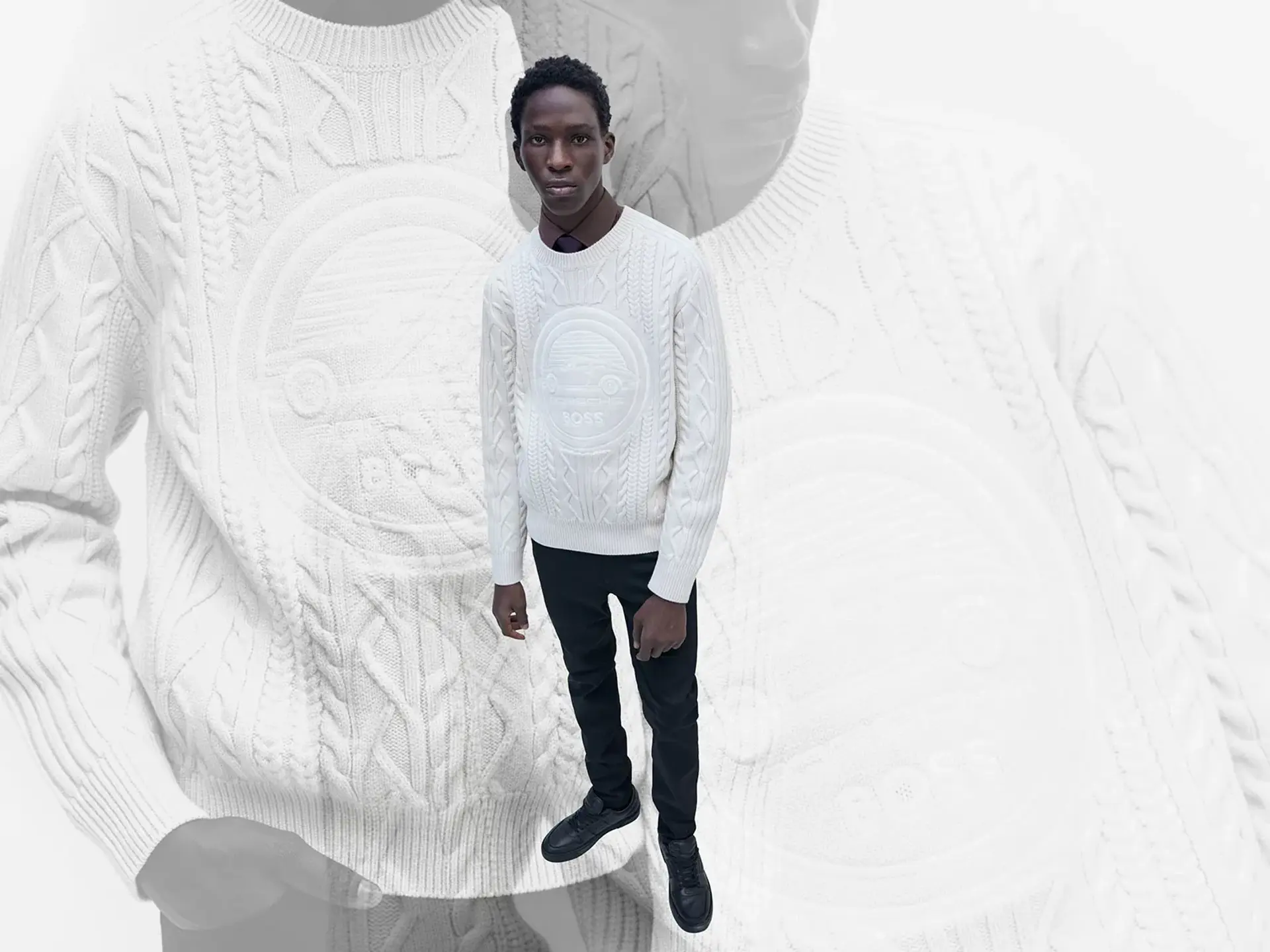 Model iført hvid kabelstrikket Porsche x BOSS-sweater og mørke bukser står foran en forstørret baggrund af samme sweater.