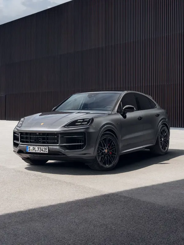 Sort Porsche Cayenne Black Edition SUV parkeret foran en mørk, moderne bygning.