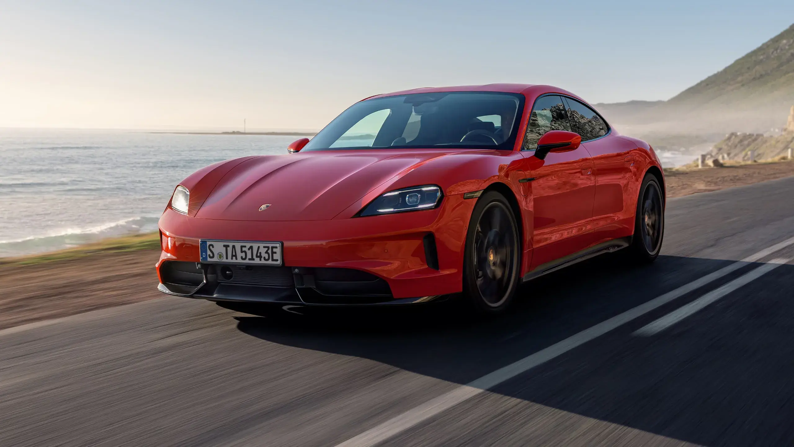 En rød Porsche Taycan ses bagfra, mens den kører gennem en kurvet bytunnel i høj fart.