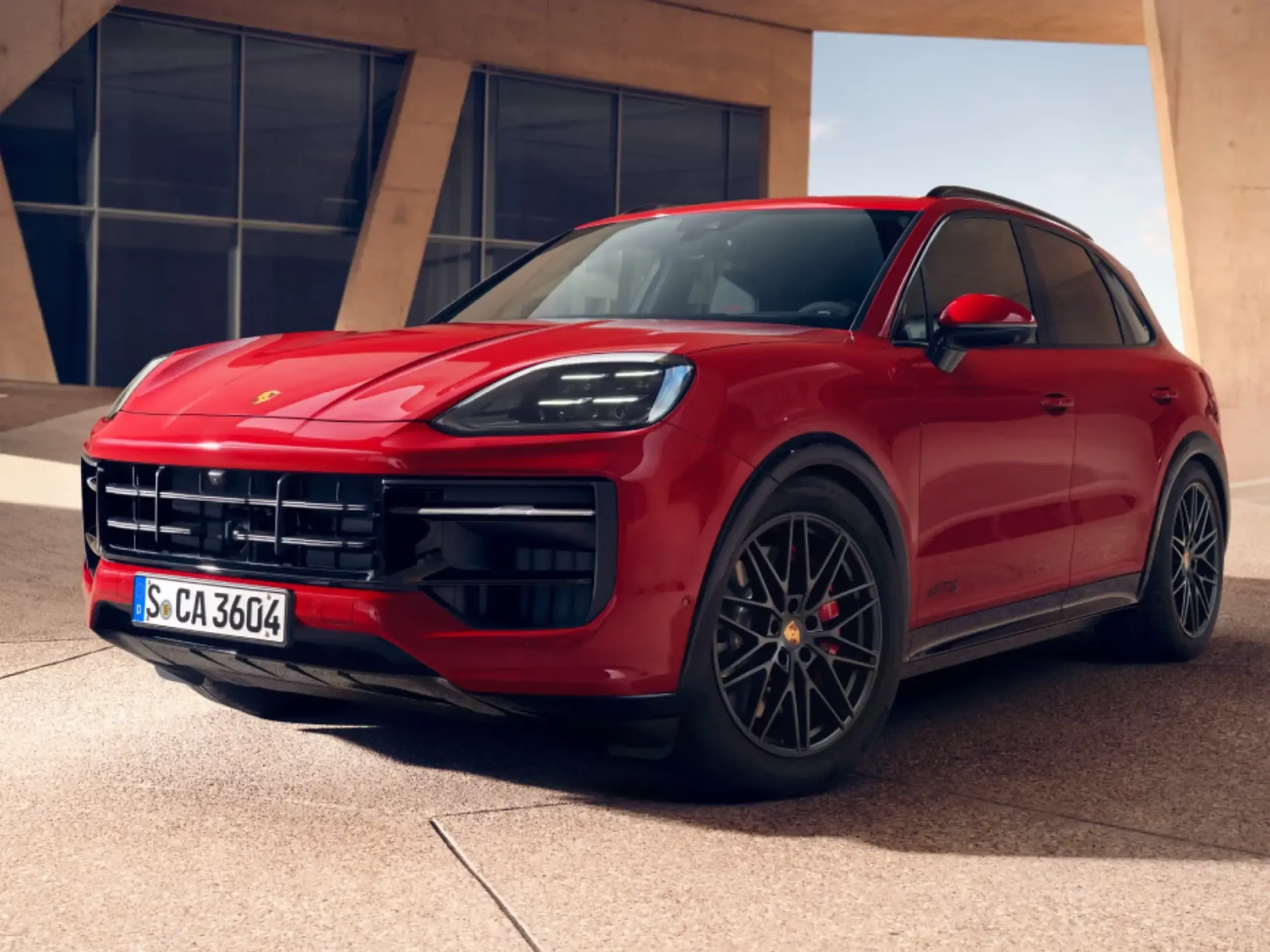 Rød Porsche Cayenne GTS SUV parkeret udendørs foran en moderne bygning.